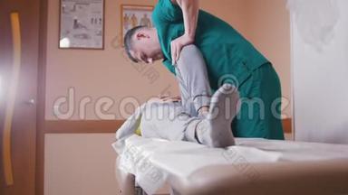 脊椎按摩师按摩躺在按摩台上的一名年轻女子，伸展和弯曲她的髋关节压在膝盖上